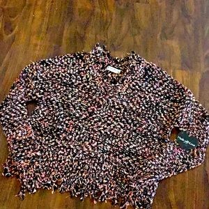 Multi-colored pinks and corals on black sweater with fringe neckline & hem